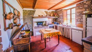 A rustic kitchen with stone walls, wooden beams, and a wooden table.