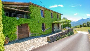 A building covered in green ivy, with a stone pathway leading to a wooden door.