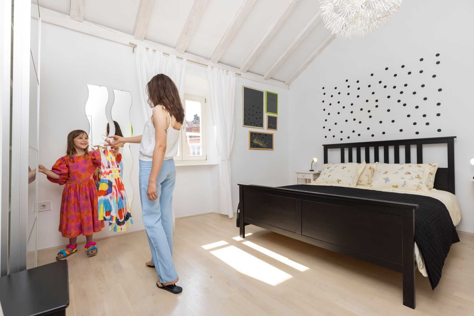 A bedroom with a bed, a nightstand, and a wall with black dots.