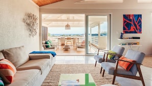 Un salon spacieux avec un plafond en bois, une grande fenêtre et une vue sur la mer.