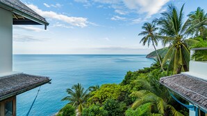 A view from a balcony overlooking a pool and the ocean, with palm trees and lush greenery. - White Azure (Ko Pha-ngan)