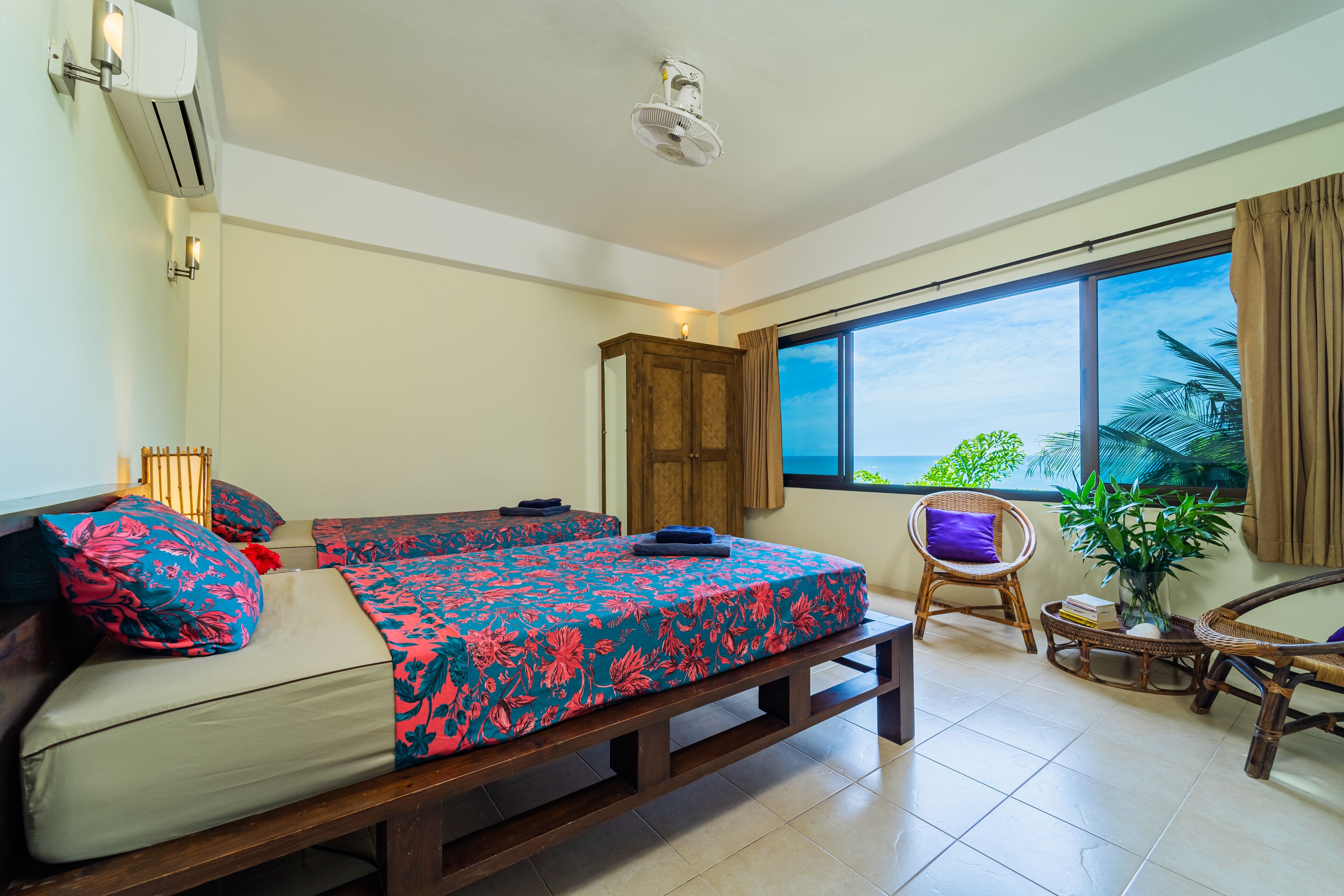 Une chambre avec un lit, une fenêtre donnant sur un beau paysage, une chaise et une plante en pot.