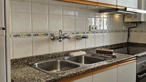 A kitchen with white cabinets, a granite countertop, stainless steel sinks, and a built-in oven. - Beautiful apartment for 4 guests with WIFI, A/C, TV, terrace and panoramic view (Altea)