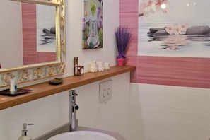 A bathroom with a mirror, sink, and decorative items on the wall.