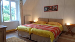 A bedroom with a large bed, two bedside tables with lamps, a window with curtains, and a framed picture on the wall. - House with garden (Plobannalec-Lesconil)
