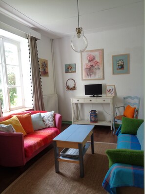 A cozy living room with a sofa, a small table, a television, and a decorative wreath.