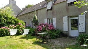 A two-story house with a garden patio, white shutters, and a door. - House with garden (Plobannalec-Lesconil)