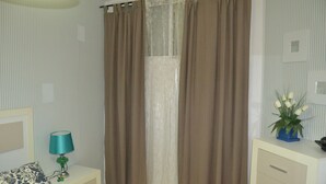 A bedroom with a bed, a nightstand with a lamp, a dresser, and a window with curtains. - 1 bedroom apartment Las Caletillas (Las Caletillas)