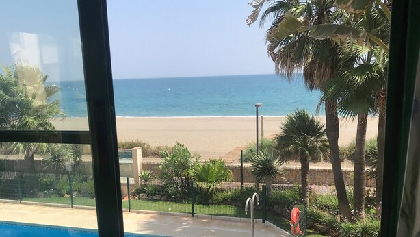 A view of a swimming pool and beach from inside a building. - Beach Diamond - fantastic duplex right on the beach close to everything (Marina de Casares)