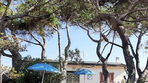 A patio area with two blue umbrellas, two lounge chairs, and a potted plant. - Apartment in Villa Valentini, Seafront, Gulf of Gaeta parking included (Minturno)