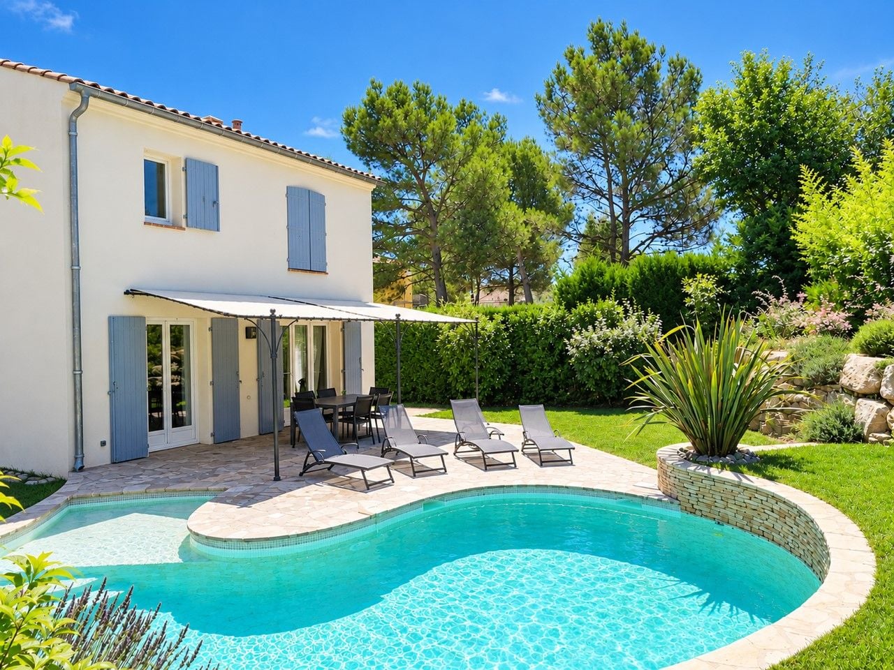 A swimming pool with lounge chairs, a covered patio, and a building with shutters.