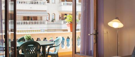 Une pièce avec un balcon, une table avec des chaises, un canapé et un lampadaire.