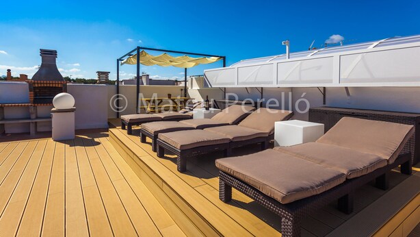 A rooftop terrace with lounge chairs, a pergola, and a white structure.