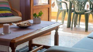 A cozy living room with a wooden table, a cushioned sofa, and a potted plant.