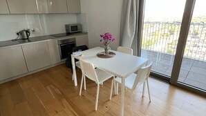 A modern kitchen with white cabinets, a dining table with chairs, and a view through a large sliding glass door. - LUXURY SERVICED APARTMENTS***** (Croydon)