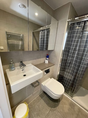 Een moderne badkamer met een wastafel, toilet en douche.