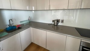 A kitchen with white cabinets, a stainless steel sink, a kettle, and a soap dish. - LUXURY SERVICED APARTMENTS***** (Croydon)