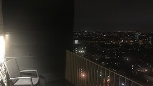 A balcony with two chairs and a small table, overlooking a cityscape at night. - LUXURY SERVICED APARTMENTS***** (Croydon)