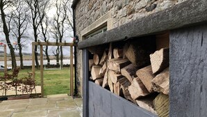 Un bâtiment en pierre doté d’une terrasse en bois et d’un chemin en pierre.