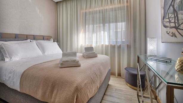 A hotel room with a large bed, a glass desk, and a painting on the wall. - Invicta Soul Joy (Porto)