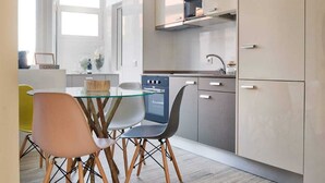 A modern kitchen with a glass dining table, wooden chairs, and built-in cabinets. - Invicta Soul Joy (Porto)