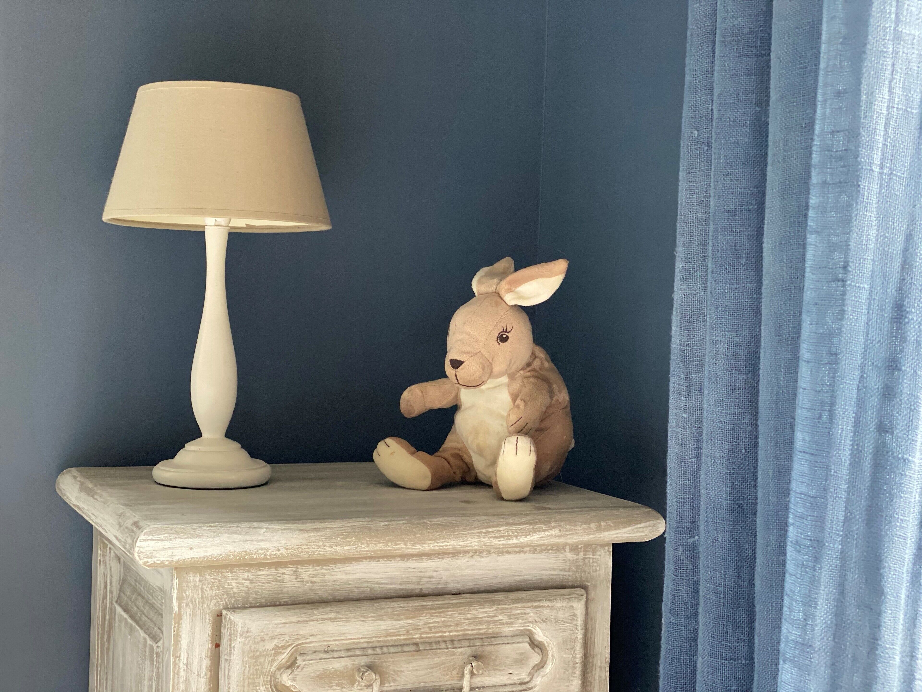 Un comodino con una lampada e un peluche.