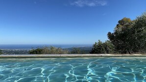 En pool med klart vand og udsigt over havet og en by i det fjerne.