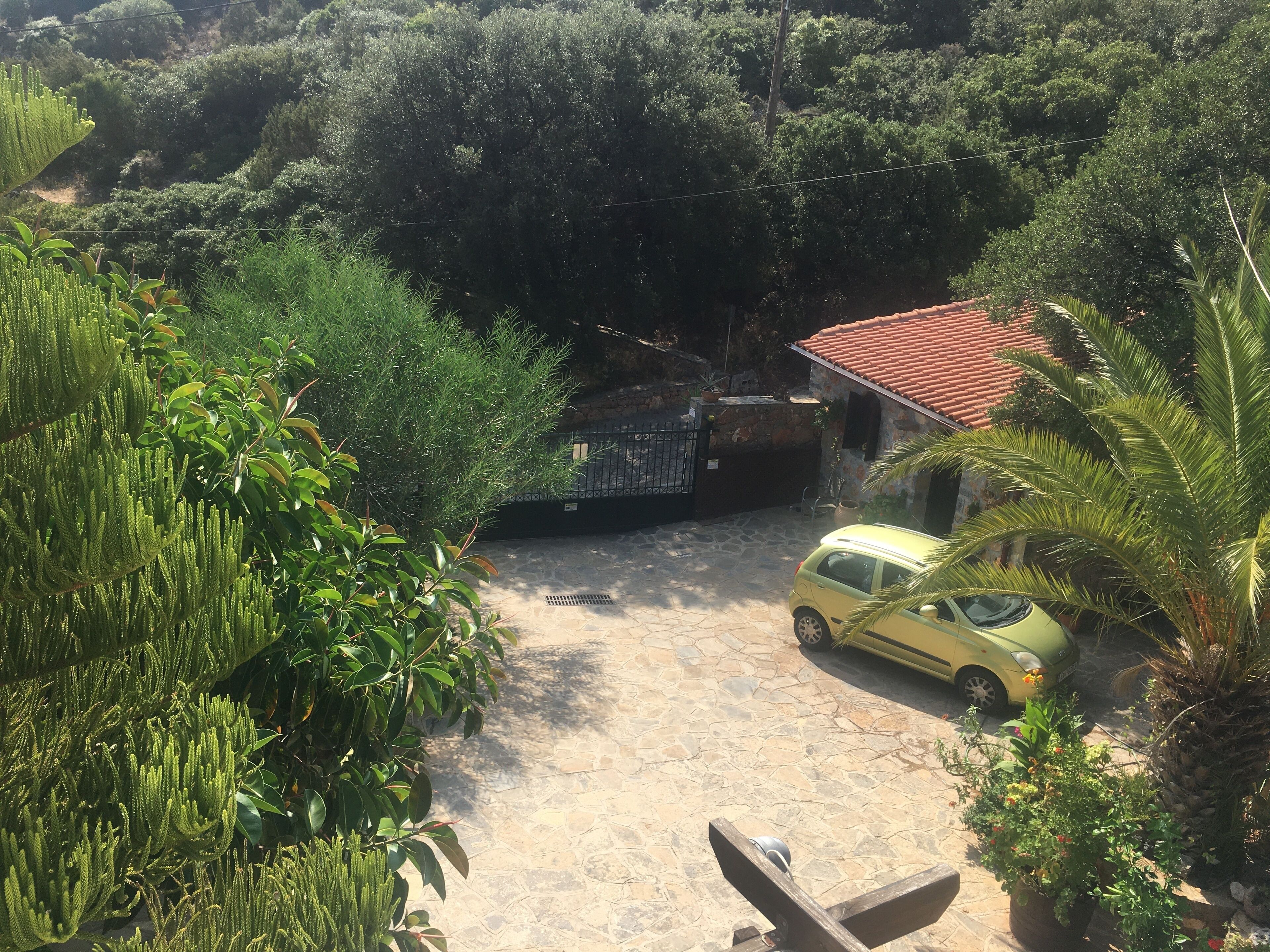 A courtyard with a yellow car parked near a building with a red-tiled roof.