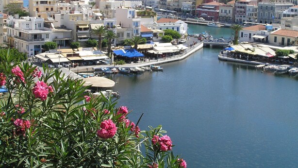 A coastal town with a marina, buildings with balconies, and a clear view of the sea.
