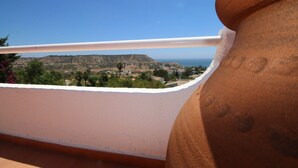 A terrace with a view of a hilly landscape and the sea.