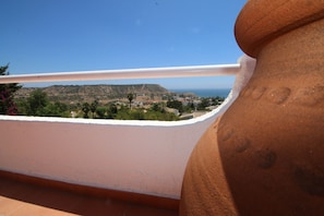 Eine Terrasse mit Blick auf eine hügelige Landschaft und das Meer.