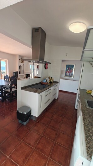 A modern kitchen with white cabinets, a granite countertop, and a stainless steel range hood. - Villa Bela Vista T3 +1 (Lagos)