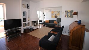 Ein Wohnzimmer mit Fernseher, Sofa und Schrank.