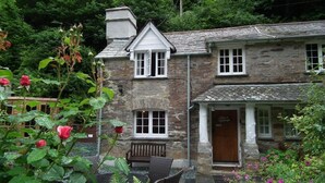 A stone building with a traditional design, featuring a pub named "Alice's Cottage" on the ground floor.