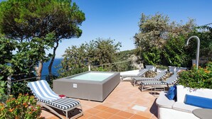 Eine Dachterrasse mit Whirlpool, Liegestühlen und Meerblick.