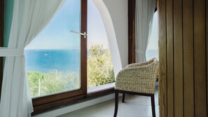 Ein Zimmer mit einem großen Bogenfenster, einem Korbstuhl und einer Holztür.