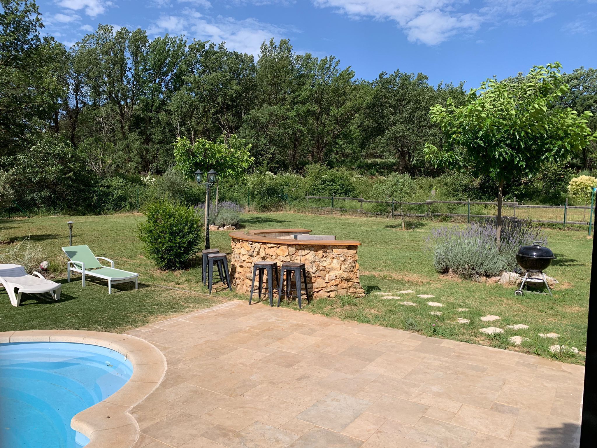 A backyard with a stone barbecue area, a pool, and outdoor seating.