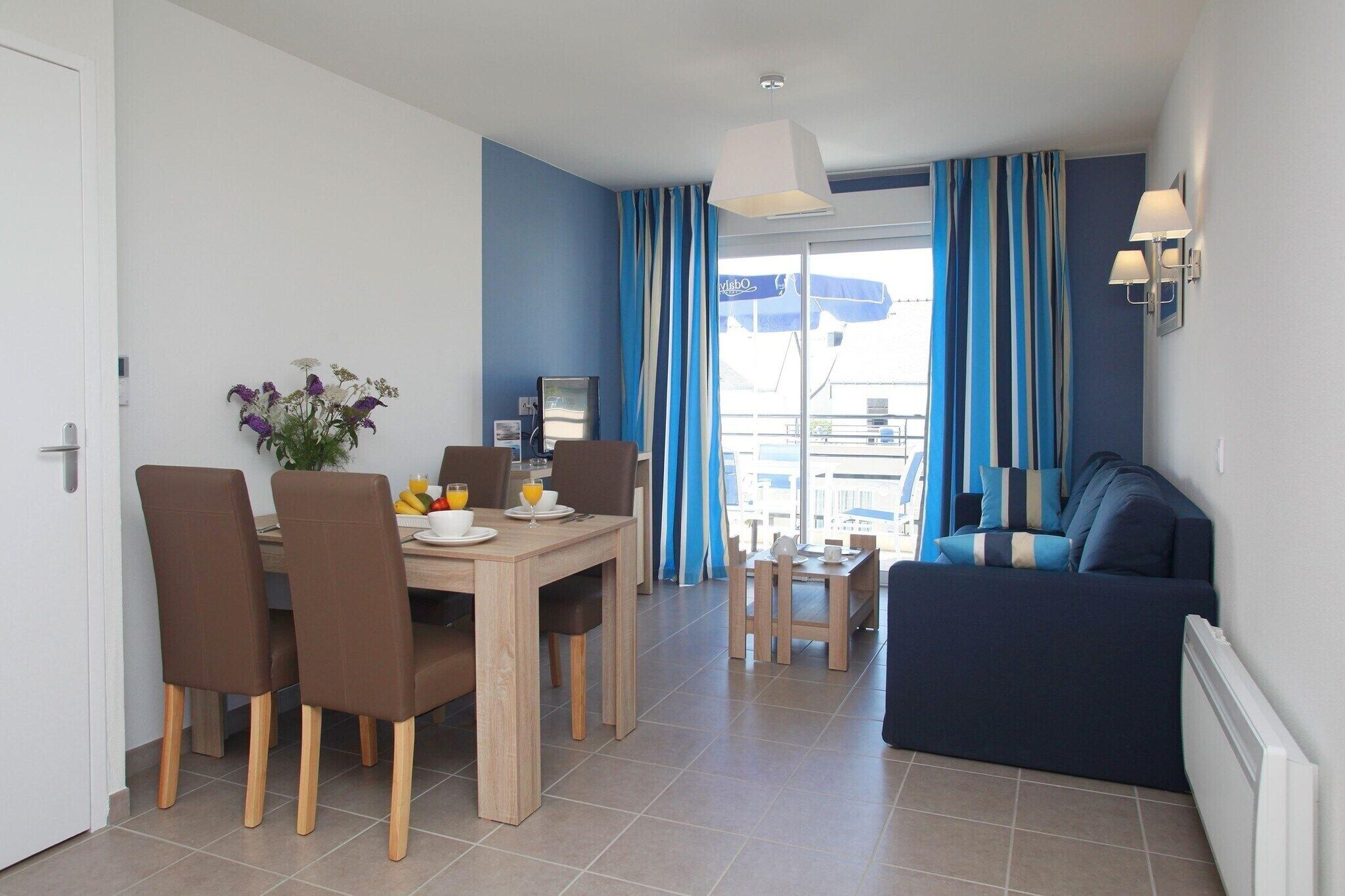 A modern living room with a sofa, a dining table with chairs, and a TV.