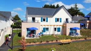 A residential building with a covered patio area, outdoor seating, and a small garden. - Apartment in Bretagne near Morbihan Coast (BADEN)