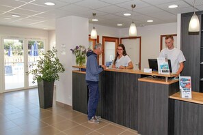 A reception area with a reception desk, a potted plant, and a sign indicating a room type.