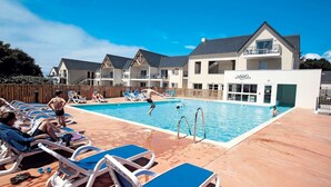 A pool area with lounge chairs and a building with a sign that reads 'OBIS'. - Apartment in Bretagne near Morbihan Coast (BADEN)