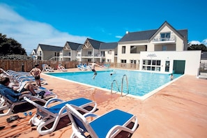 A pool area with lounge chairs and a building with a sign that reads 'OBIS'. - Apartment in Bretagne near Morbihan Coast (BADEN)