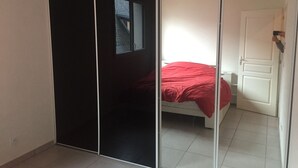 Una habitación con cama, puerta corredera y acceso a otra habitación.