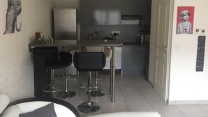 Una cocina moderna con armarios grises, un refrigerador de acero inoxidable y una barra con taburetes negros.