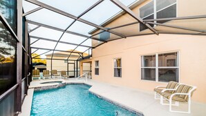 A swimming pool with a glass enclosure, lounge chairs, and a patio area. - Spacious Villa In Emerald Island Resort, Kissimmee / Orlando, Florida, USA (Kissimmee)