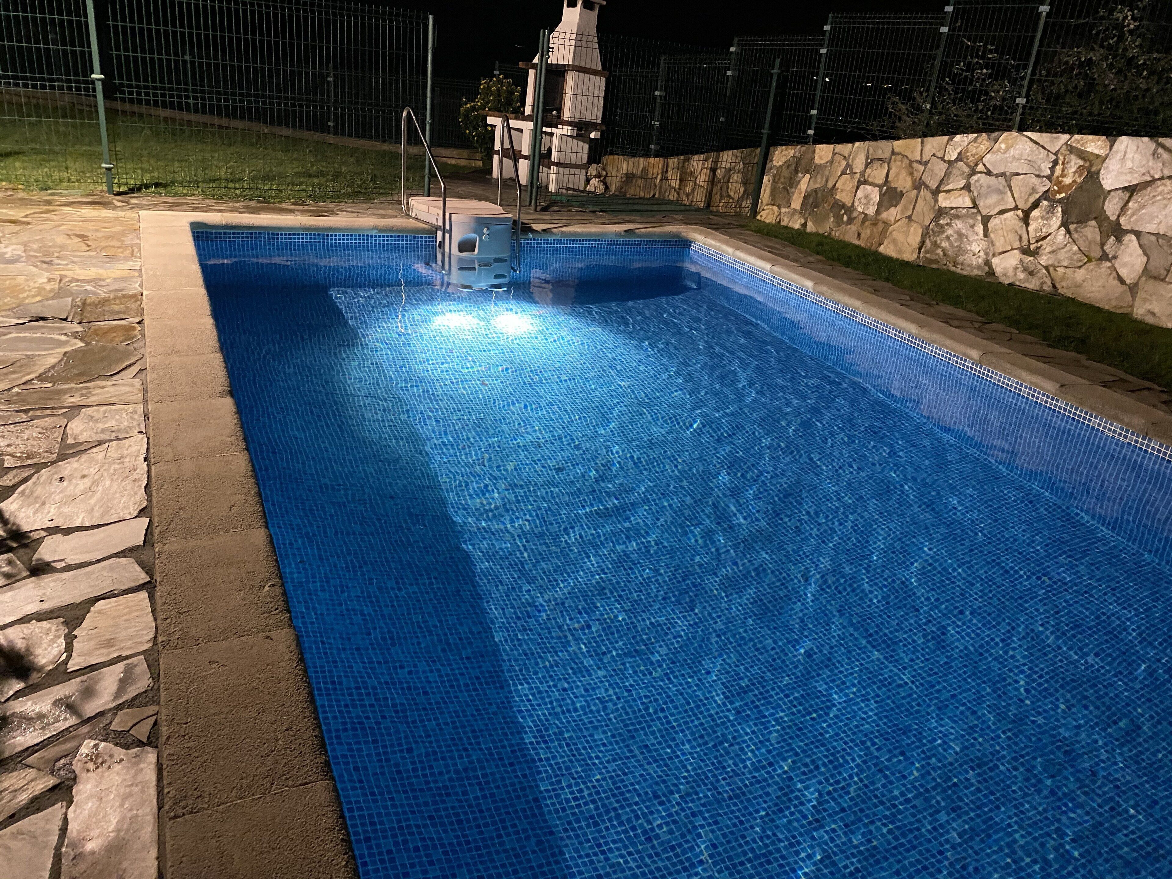 Une piscine bordée de pierres et dotée d’un escalier en métal.