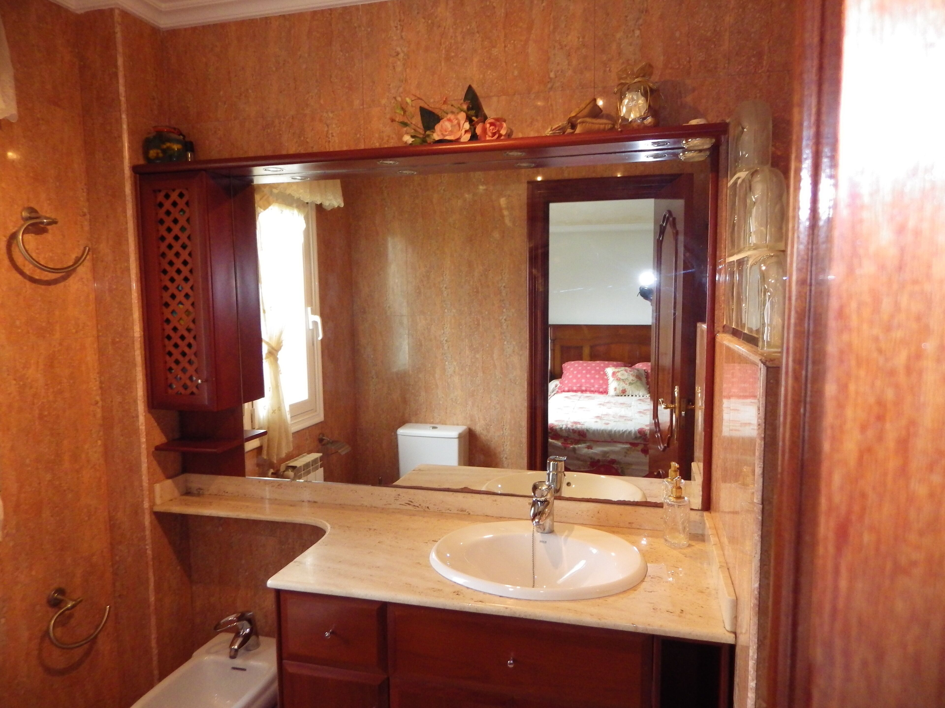 Un baño con un espejo grande, un lavabo y un inodoro.