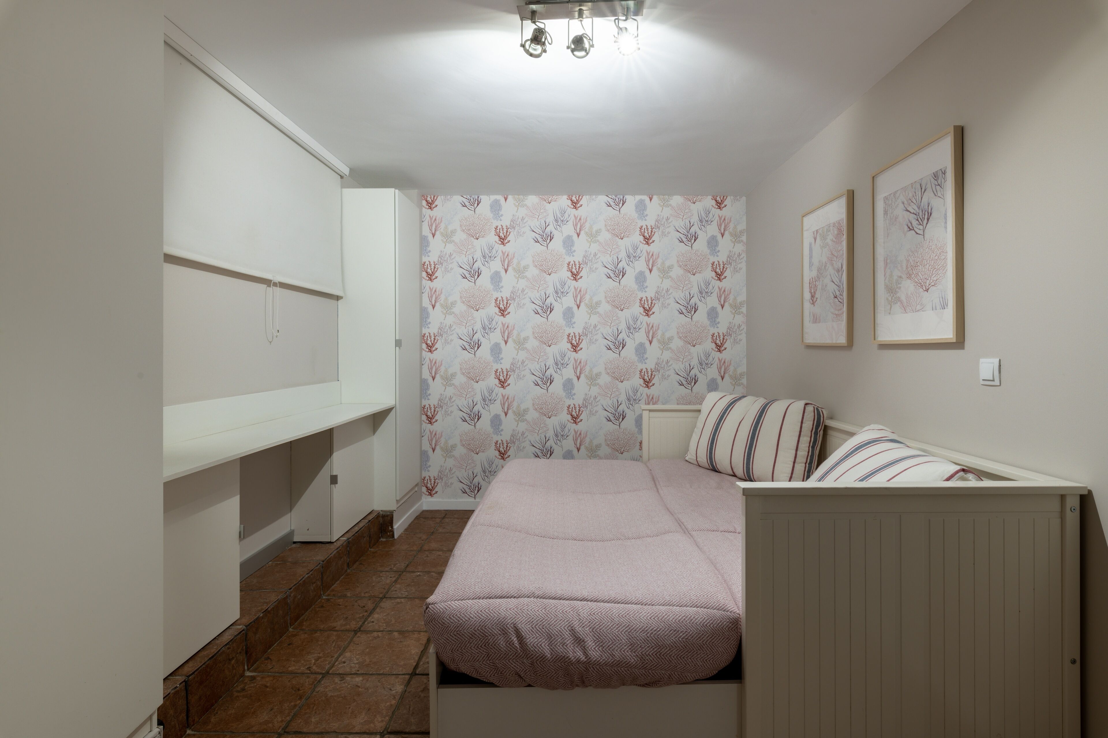Un dormitorio con cama, armario y pared con papel tapiz floral.