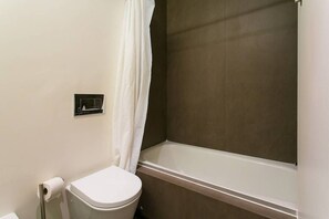 Ein Badezimmer mit Toilette, Duschvorhang und Badewanne.