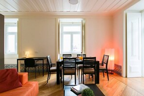 Ein Essbereich mit einem Tisch für vier Personen, einer Couch und einer Lampe.